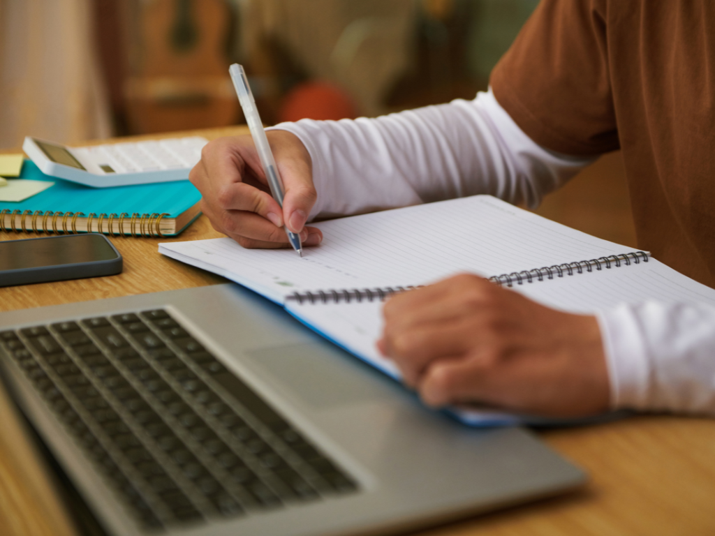 Imagen de un alumno de curso online escribiendo en su libreta