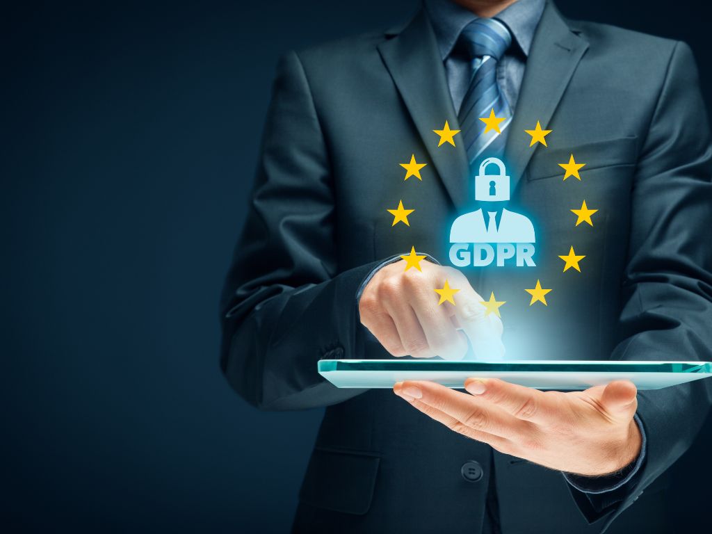 Persona con traje con una tablet en la mano que enseña el logo europeo del GDPR