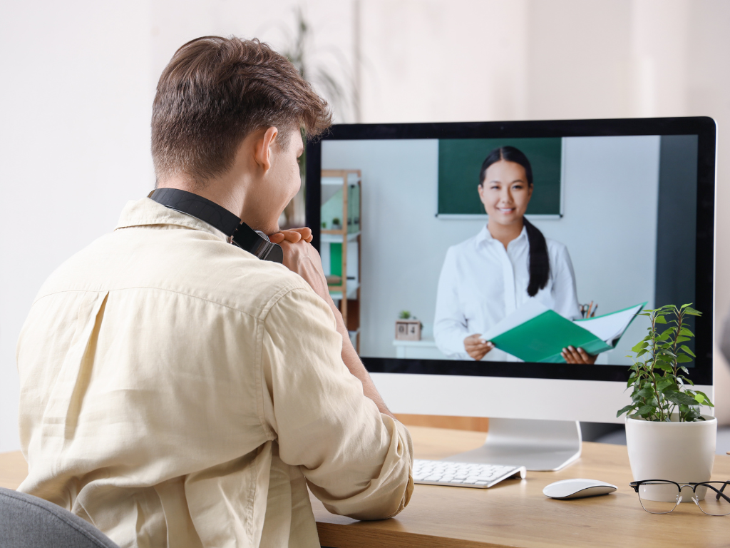 Alumno de curso online viendo a su profesora en directo a través de su ordenador